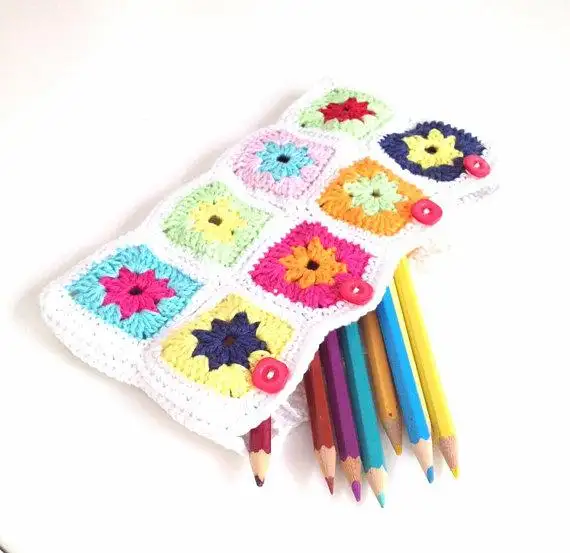 Colorful flower granny-square crochet pencil case with pencils and four pink buttons