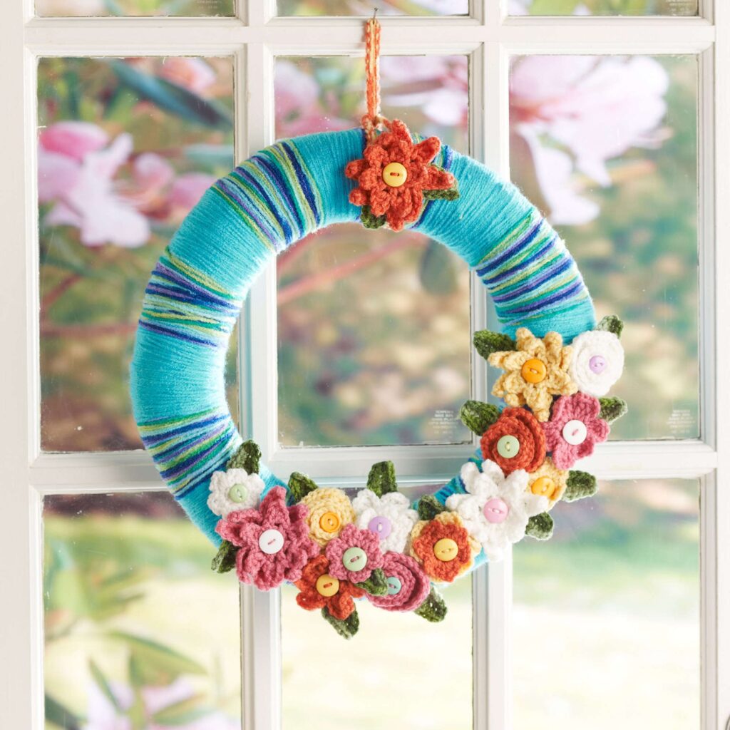 Colorful crocheted flower wreath hanging in a window