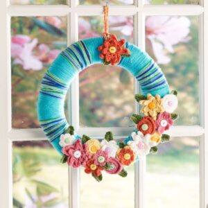 Colorful crocheted flower wreath hanging in a window