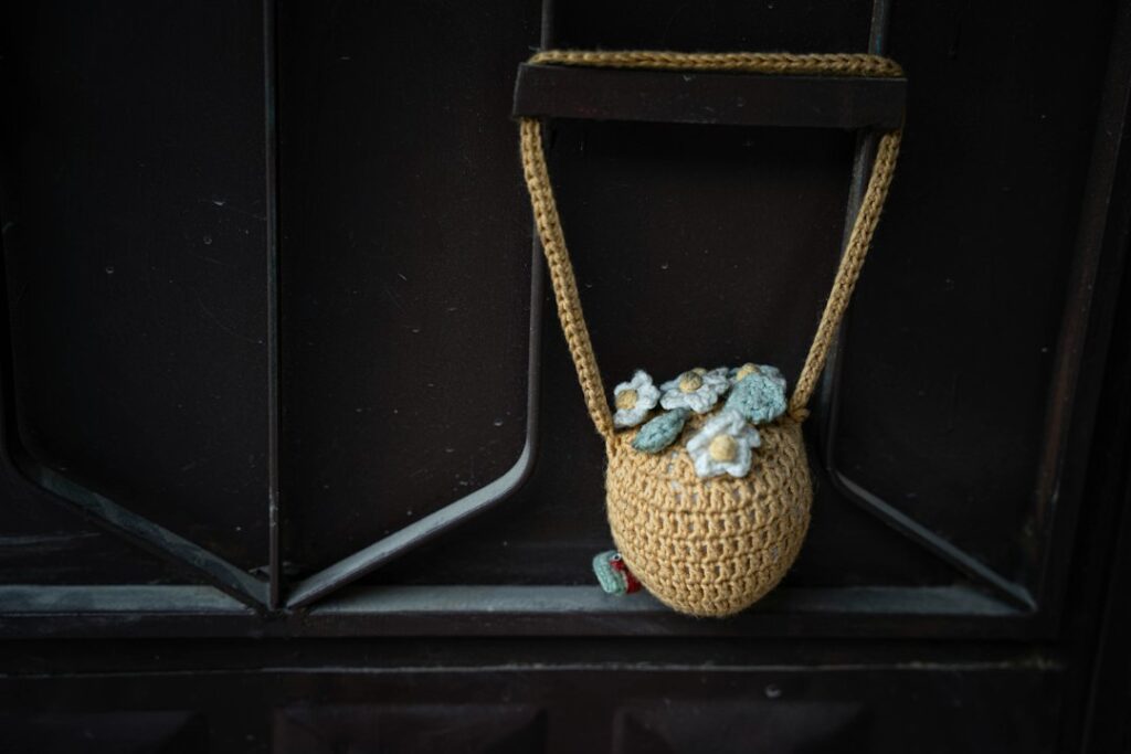 Small yellow crocheted shoulder bag with a strap and floral details