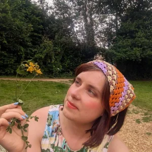 Woman wearing a lilac peach and cocoa granny crochet bandana outdoors