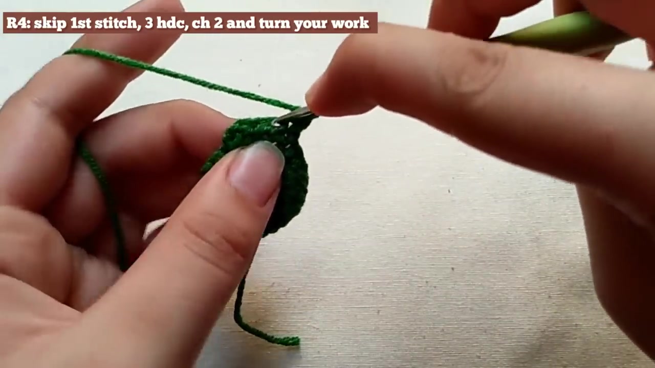 Green crochet rose calyx point being tapered with half double crochet stitches