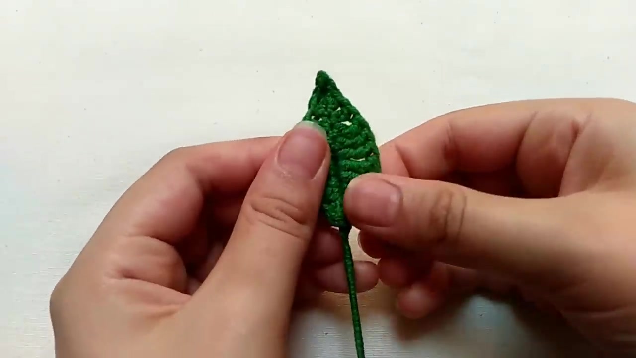 Completed pointed green crochet rose leaf shaped over a thin wire