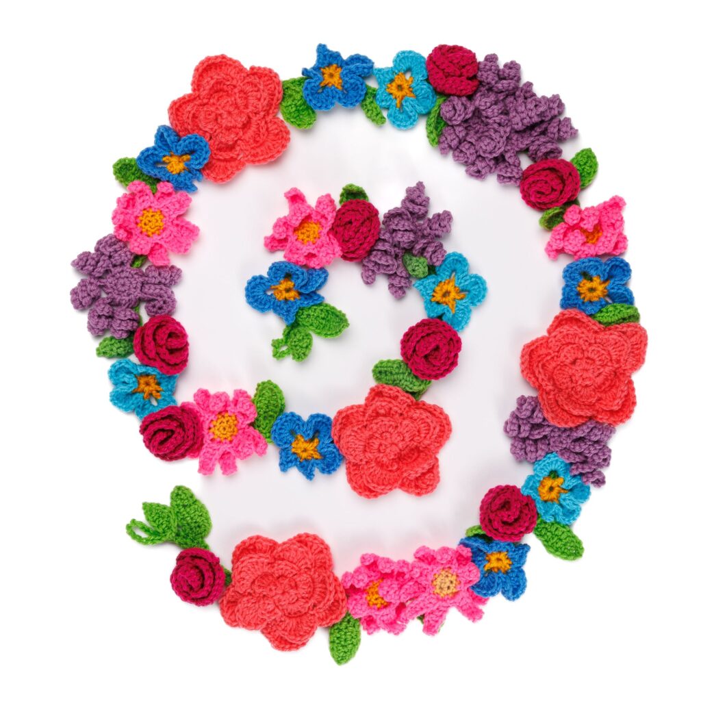 Colorful crocheted floral garland arranged in loops with roses, pansies, daisies and leaves
