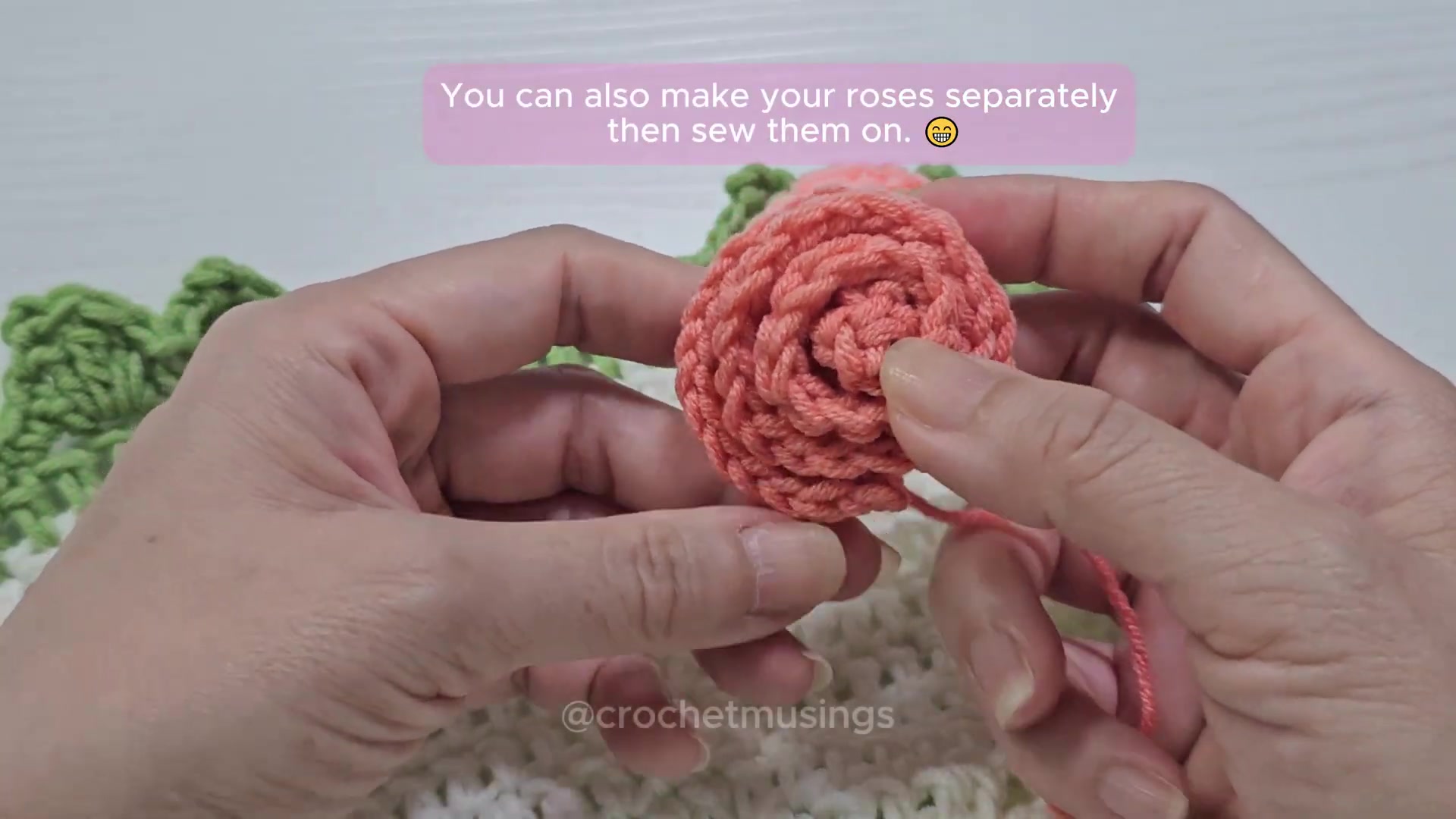 Finished rolled pink crochet rose held over the blanket