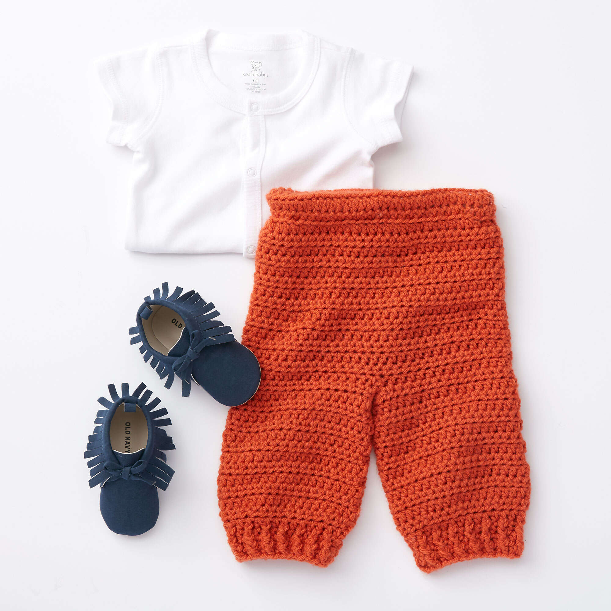 Orange Bernat Smarty Pants crochet baby trousers displayed with a white top