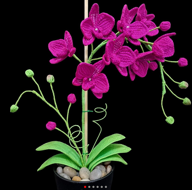 Purple crocheted orchid flowers on green stems in a decorative pot