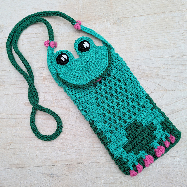 Green frog-themed crochet phone pouch with large eyes and a long strap