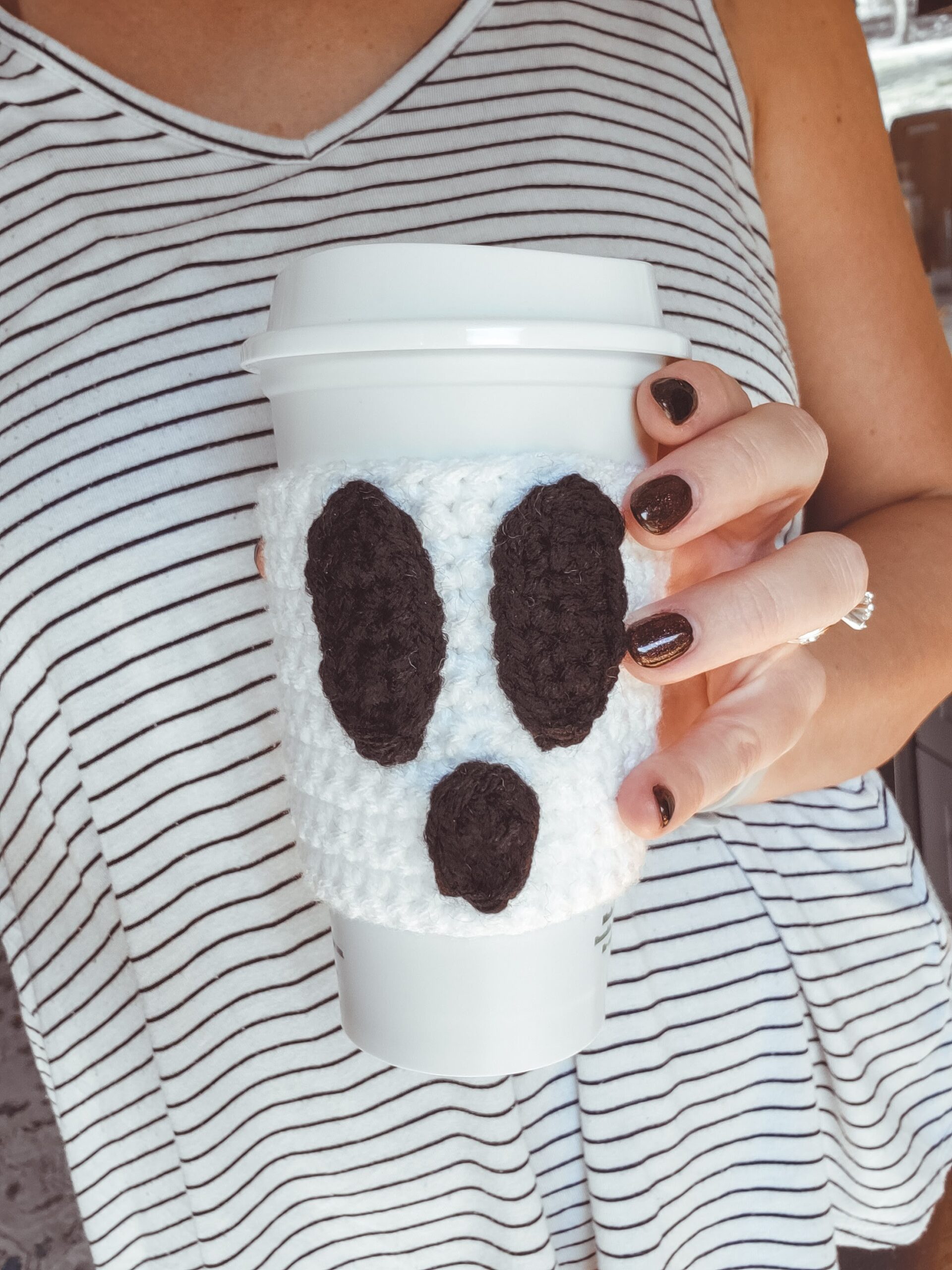 White crochet ghost cup cozy with black eyes and mouth by Heather Corinne
