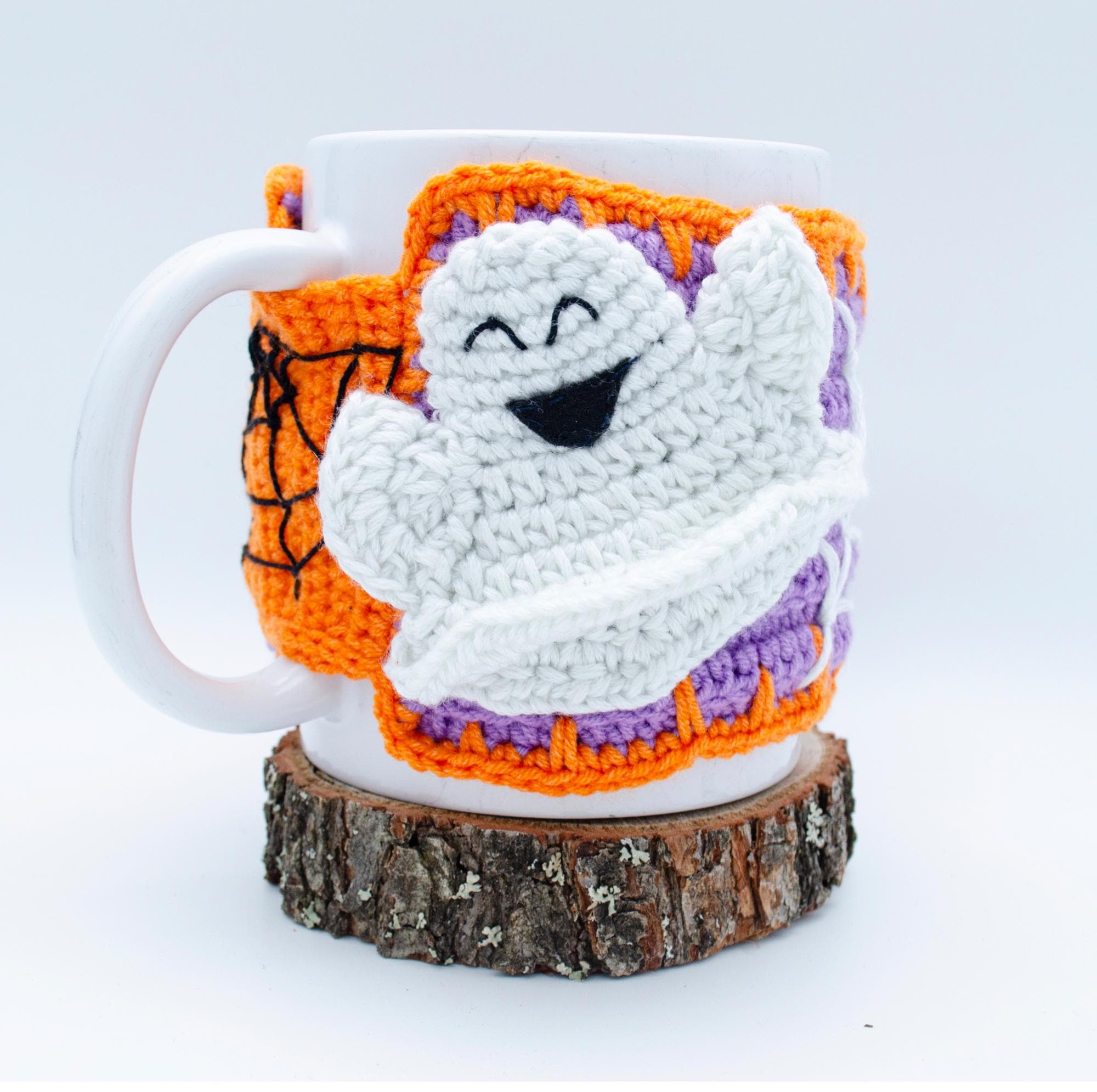 Purple and orange crochet Halloween mug cozy with white ghost and spiderweb by KnittingKittyDesigns