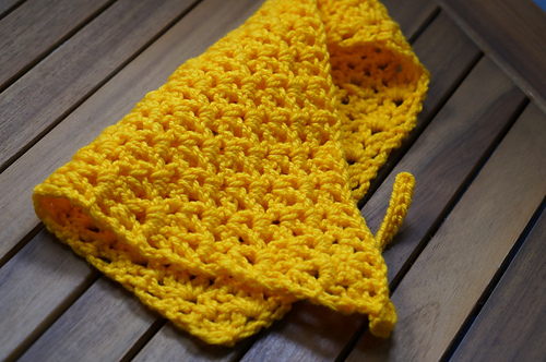 Yellow V-stitch crochet bandana laid flat with ties at the sides