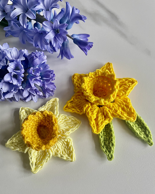 Small yellow crochet daffodils with green leaves by Munira Rasul