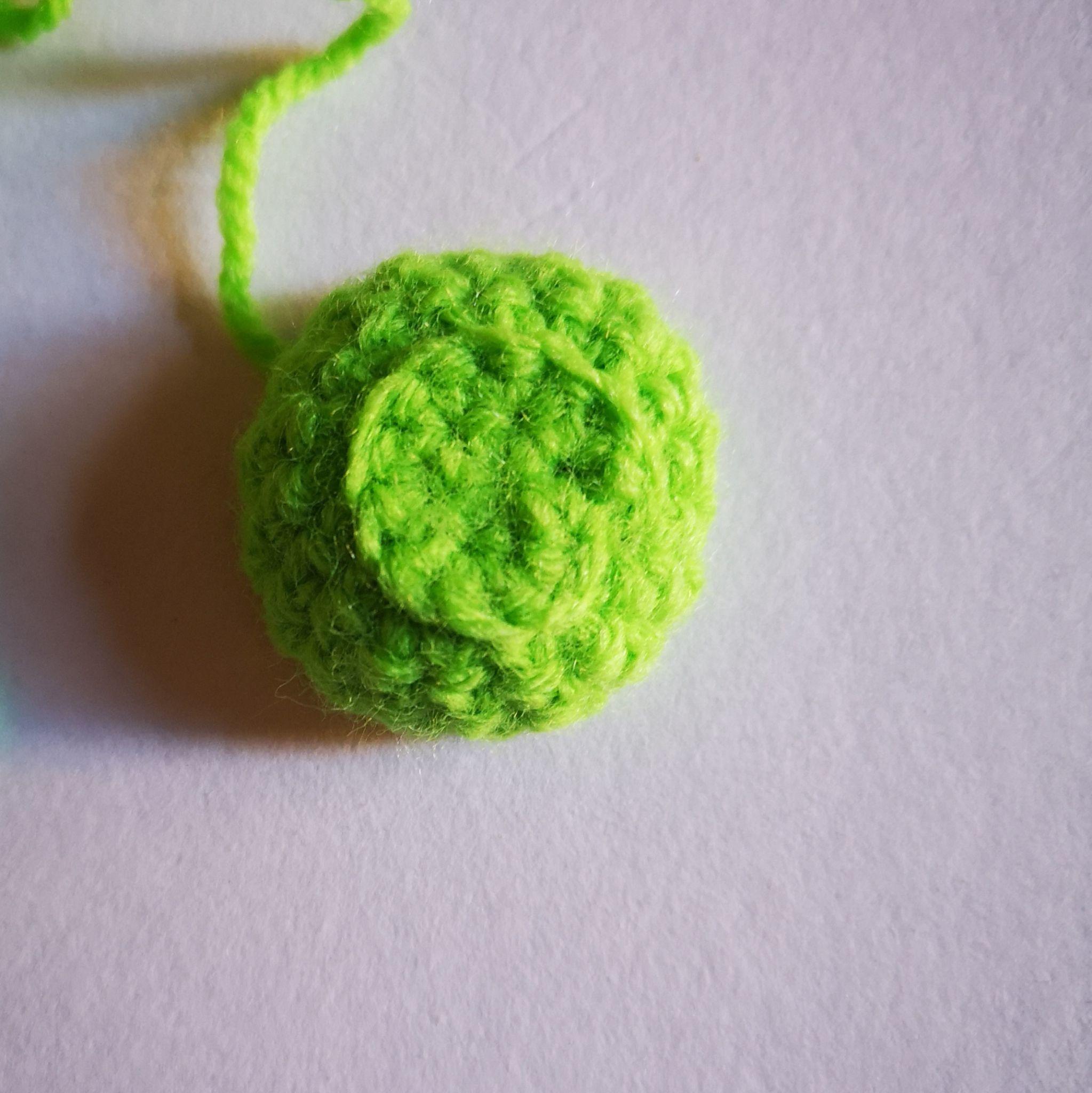 Small green crocheted flower base with its open underside visible