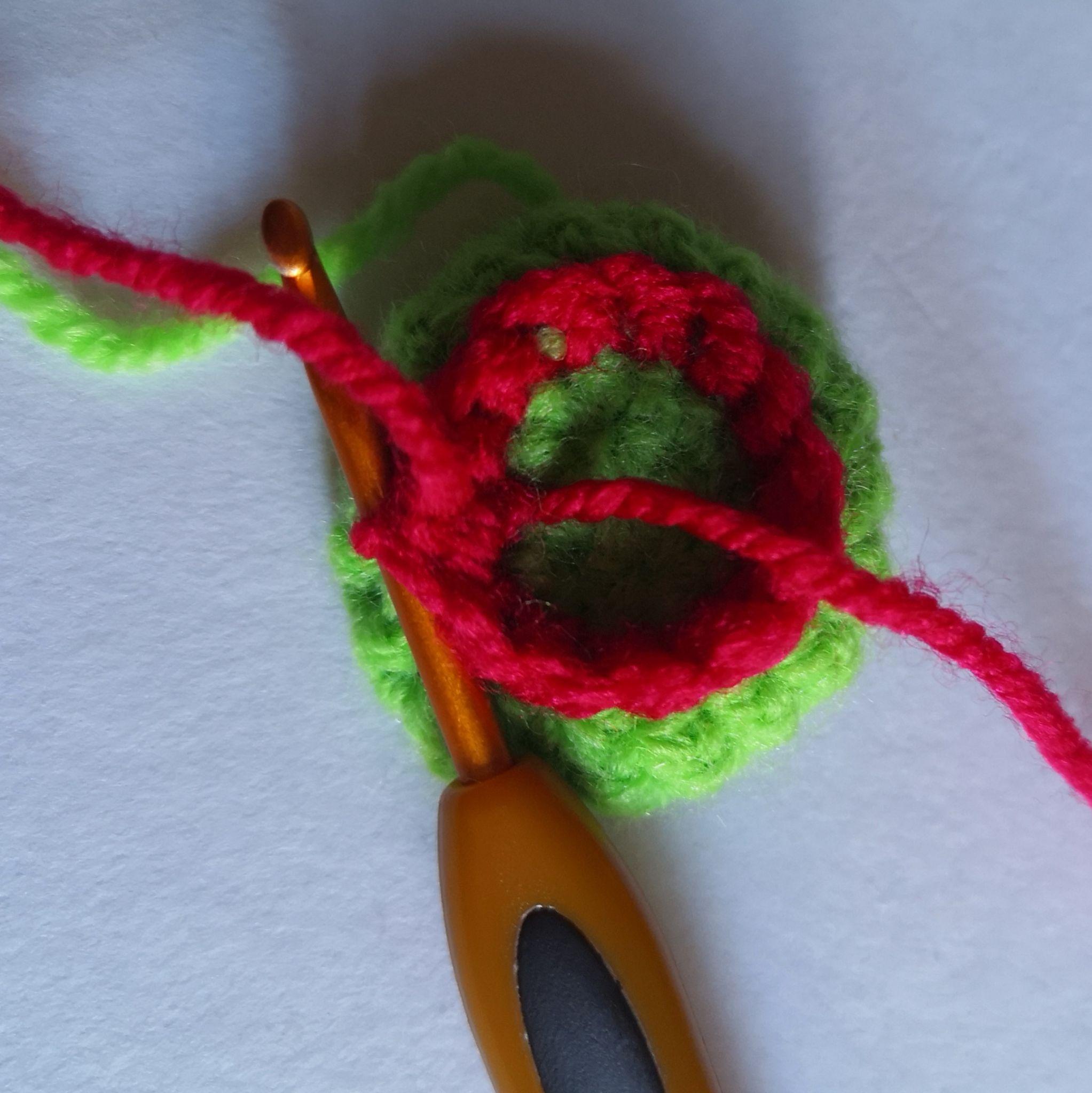 Red yarn being joined to the reserved loops of a green crochet base
