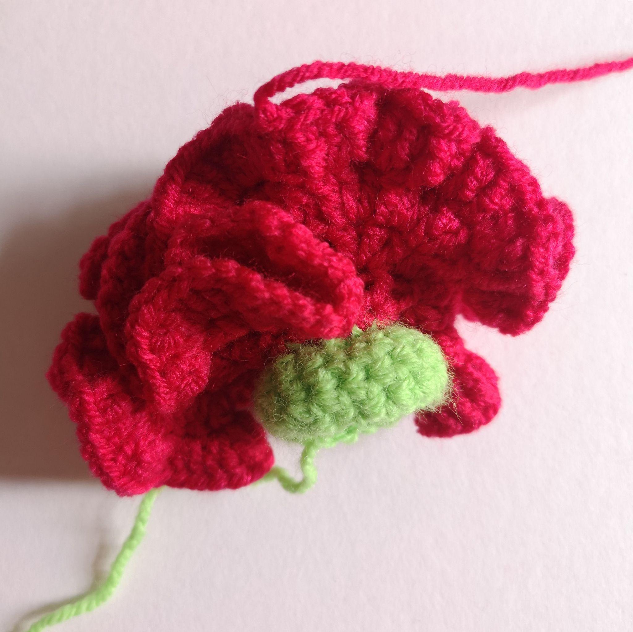 Red crocheted petal layers expanding around a green base