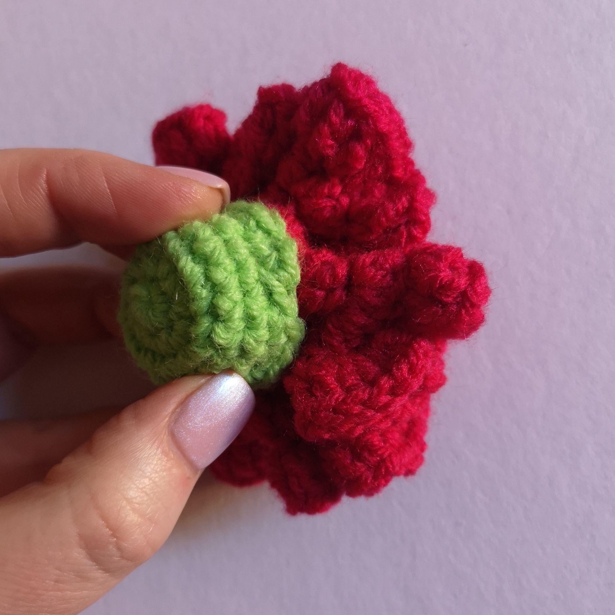 Green crocheted base covering the underside of red carnation petals