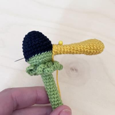 Yellow crochet petals being sewn around the flower center