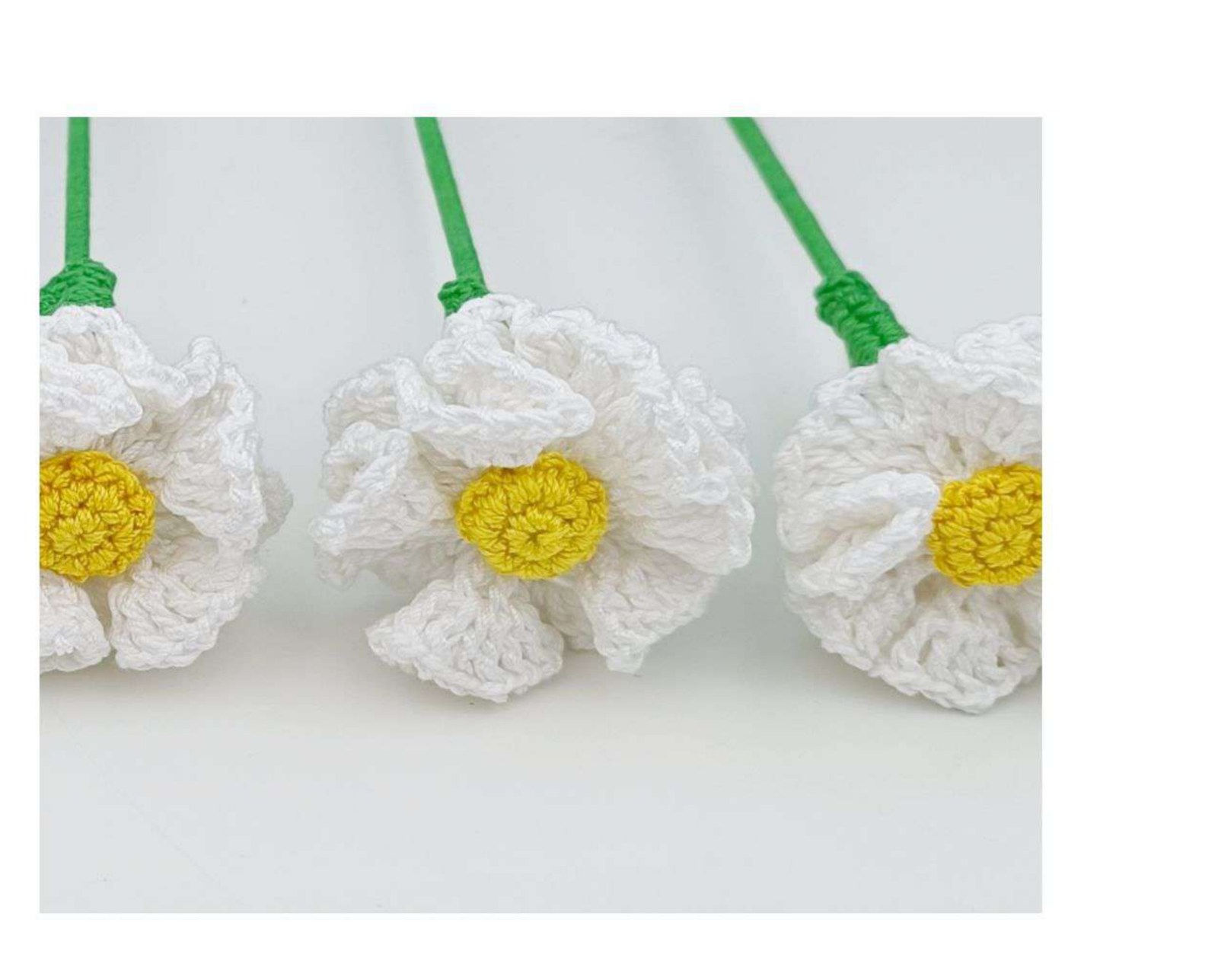 White crochet daisies with yellow centers on green stems