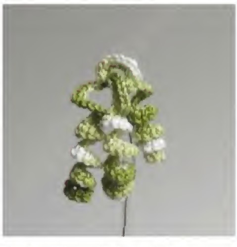 Three green crochet curly grass branches on a thin stem