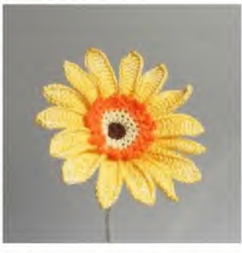 Yellow crochet gerbera daisy with an orange looped ring and brown center