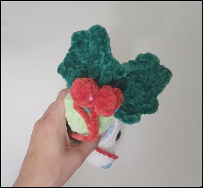 Holly and red berry pieces beside a crochet cactus in a polar bear pot