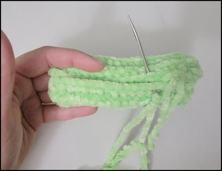 Sewing a green ribbed crochet cactus into a tube