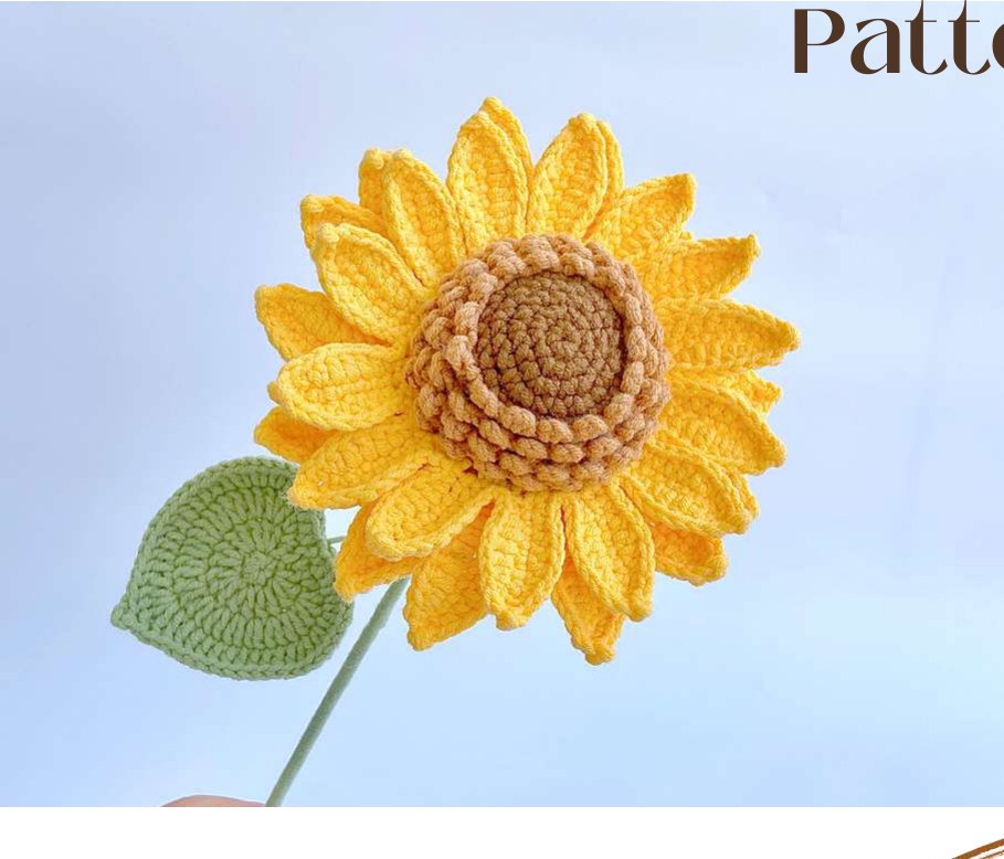 Crochet sunflower with a textured brown center, yellow petals and a green leaf
