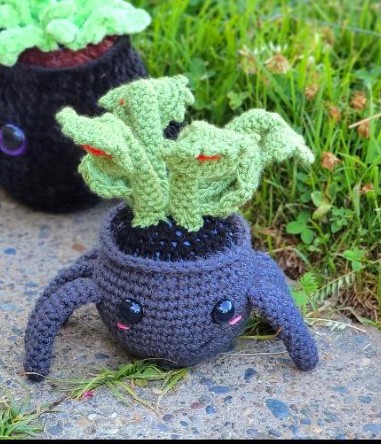 Crochet Venus flytrap with four green trap heads on a dark spider-shaped pot