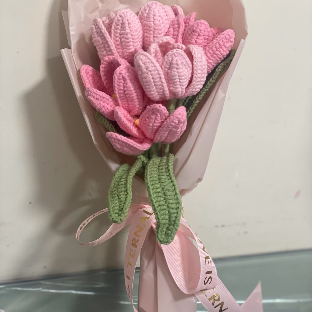 Wrapped pink crochet tulip bouquet with long green leaves and a ribbon