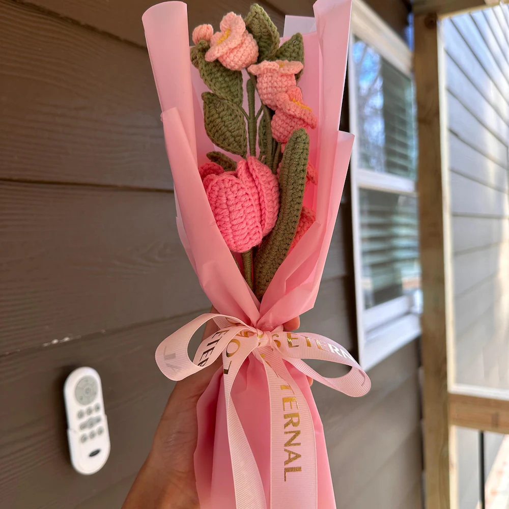Single bright pink crochet tulip and small peach flowers in narrow pink gift wrapping