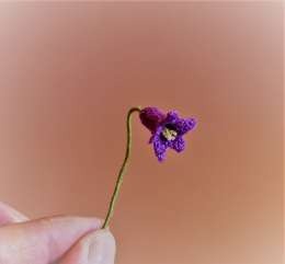 Miniature purple crochet bluebell on a green thread-wrapped stem
