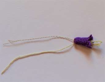 Thin wire inserted behind a miniature bluebell with yellow thread stamens