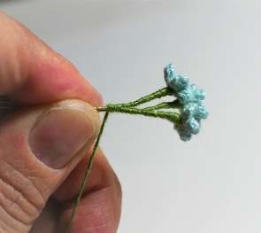 Joining three miniature flower stems with green thread